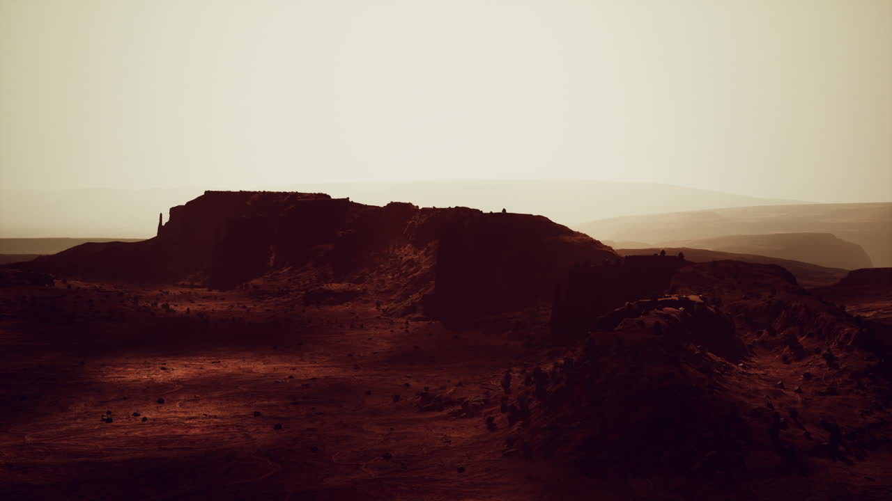 un paisaje desértico rojo con una cordillera en la distancia