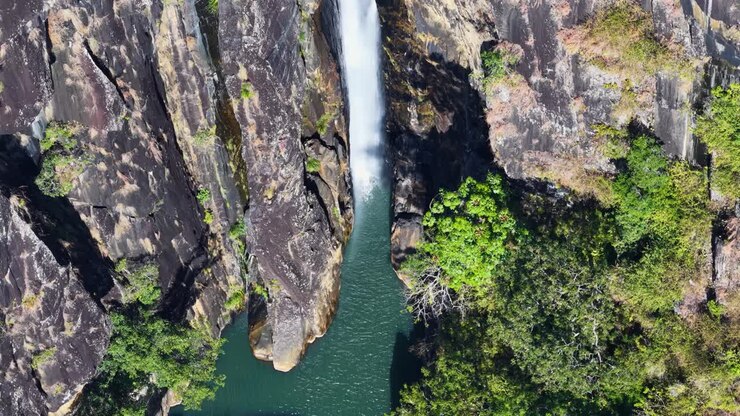 Drone footage captures a stunning waterfall cascading into a lush, green rainforest in Port Douglas, Australia