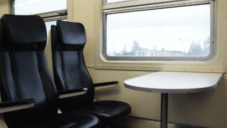 dos asientos vacíos con mesa en el tren en movimiento