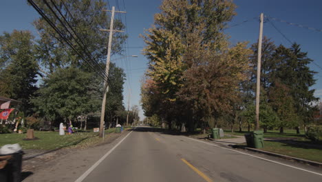 drive along a typical street of an american town on a clear autumn day. the sun illuminates houses and trees beautifully. 4k shot