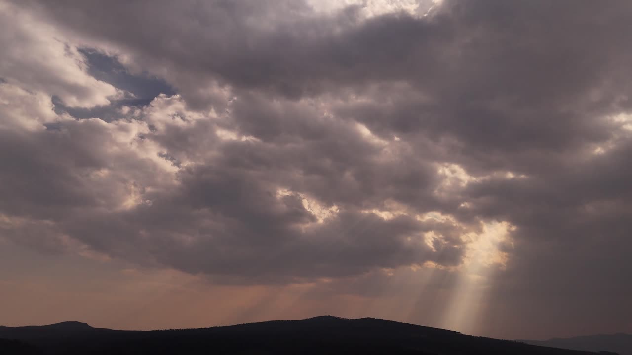 Sunshine breaks through the dark clouds, casting a beautiful light over the dramatic cloudscape.