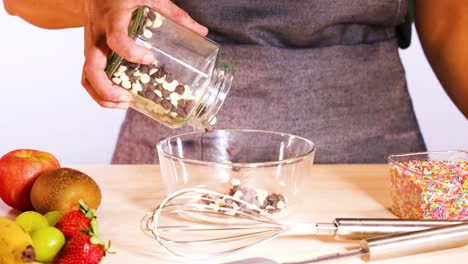 person pouring chocolate chips into a bowl