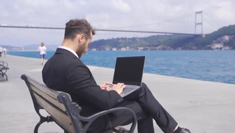 focused and serious businessman. he works by the sea. slow motion.