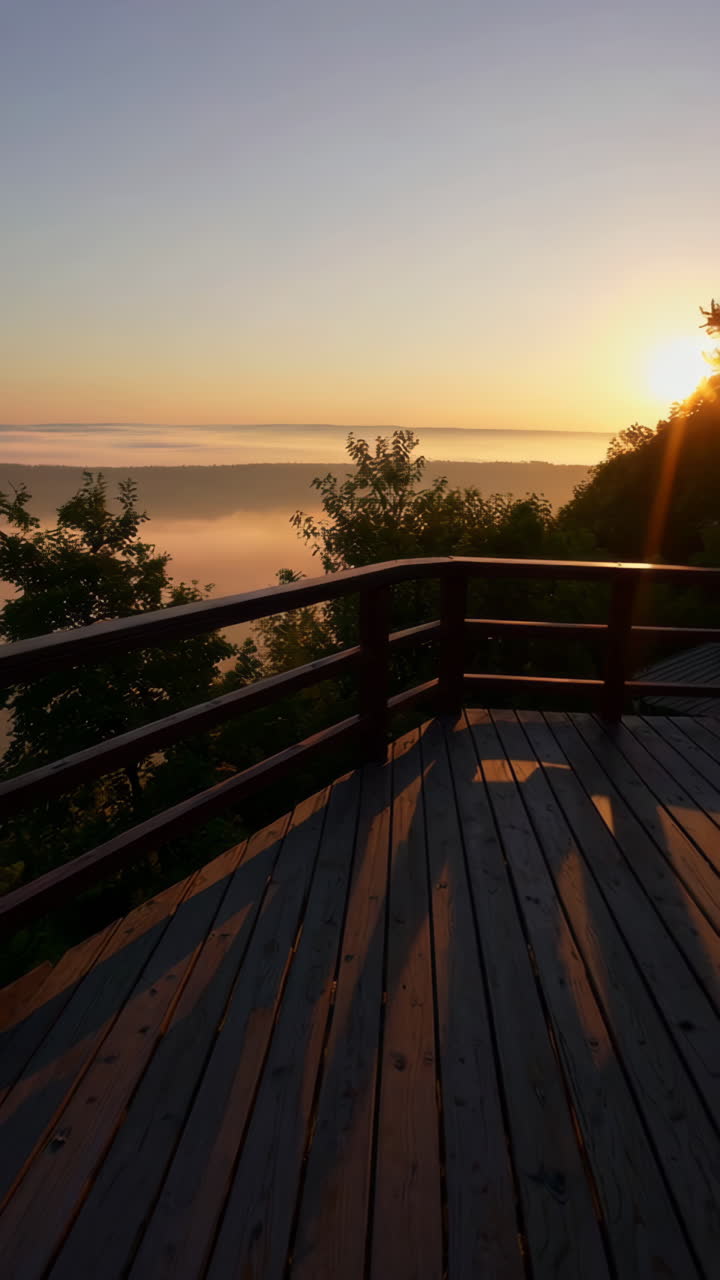 Auringonnousu sumuisten vuorten yllä puiselta näköalapaikalta