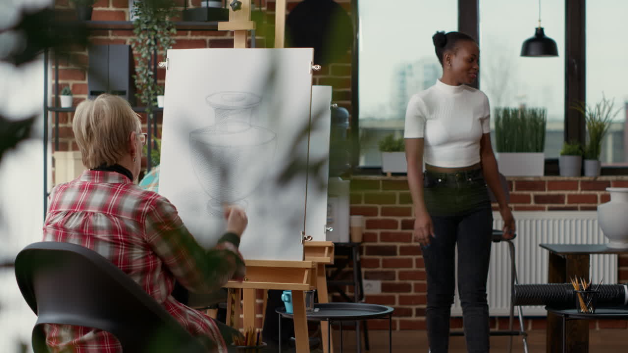 Art teacher training senior woman to draw artwork in art class