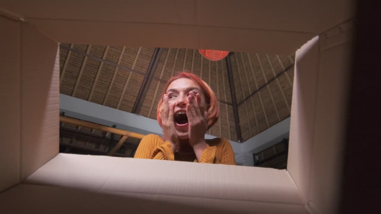 Young caucasian woman opens box and rejoices to see pleasant surprise