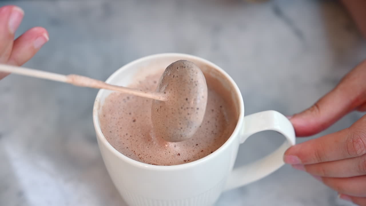 Donna che mescola cioccolato nel latte in una tazza bianca in un bar