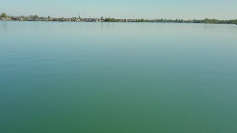 aerial drone shot of flying low at the lake and moving forward revealing the suburban near the lake in the netherlands.