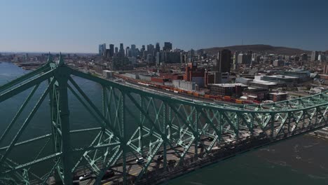 drone close up of the jacques cartier bridge revealing cityscape of montreal city at distance aerial skyline