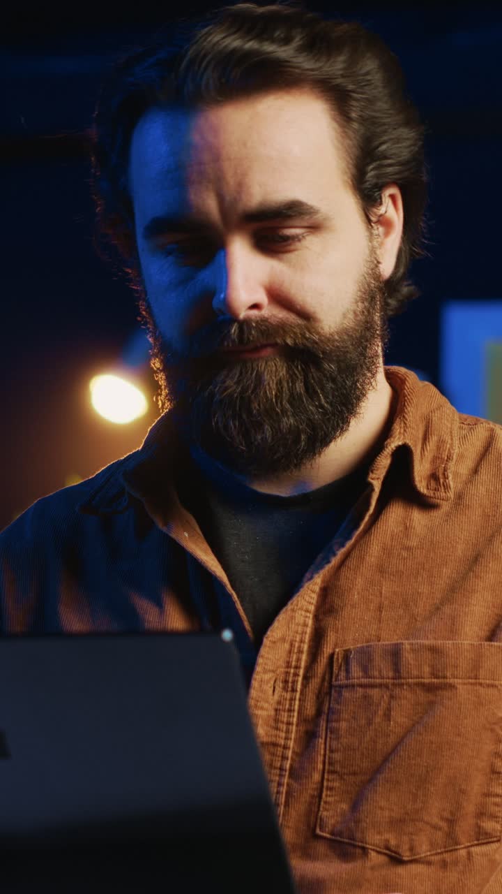 Focused Man Coding on Laptop in Dark Office