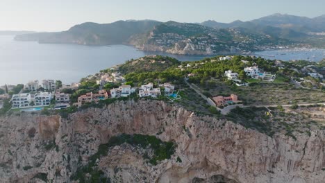 aproximación aérea hacia el escarpado acantilado costero con edificios, mallorca