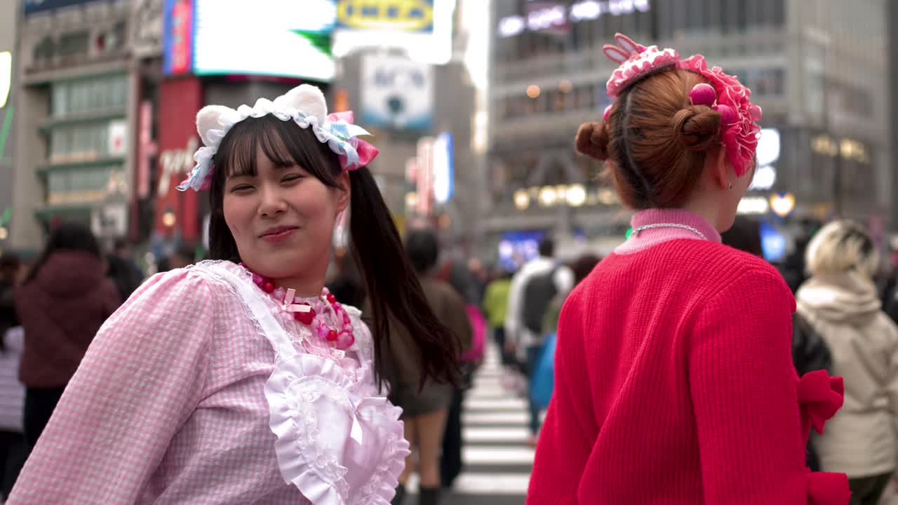 Due donne in vivace stile decora ballano e ridono all'affollato incrocio di Shibuya.