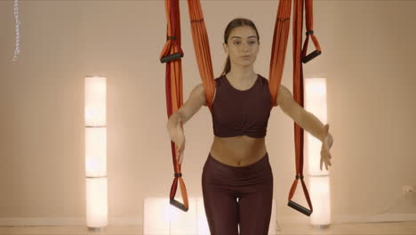 woman stretching hands at yoga class. girl doing yoga with hammock in studio