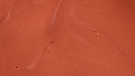 a detailed view of chocolate disks partially submerged in a glossy liquid.