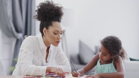 African-american-mother-and-daughter-sitting-and-table-and-doing-homework-together,-slow-motion