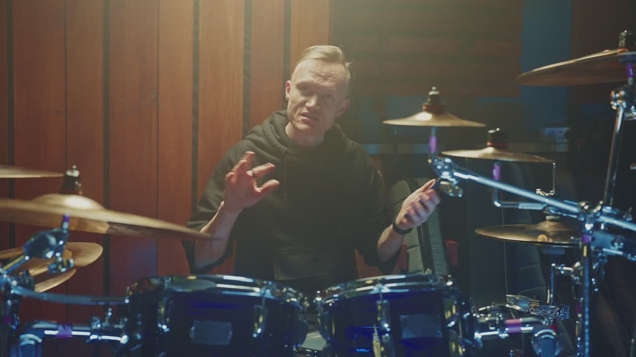 Drummer checking phone in music studio