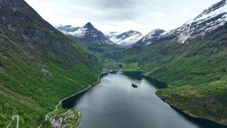 Stunning-Geiranger-Fjord-with-mountain-scenery-in-background---Forward-moving-aerial-from-eagles-road-looking-towards-Geiranger-village-with-a-cruise-ship-at-anchorage