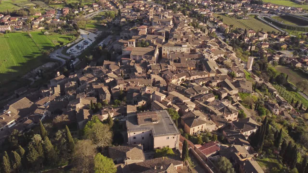 Backwards aerial view of town of Spello. Umbria, Italy, clear sky, 4k