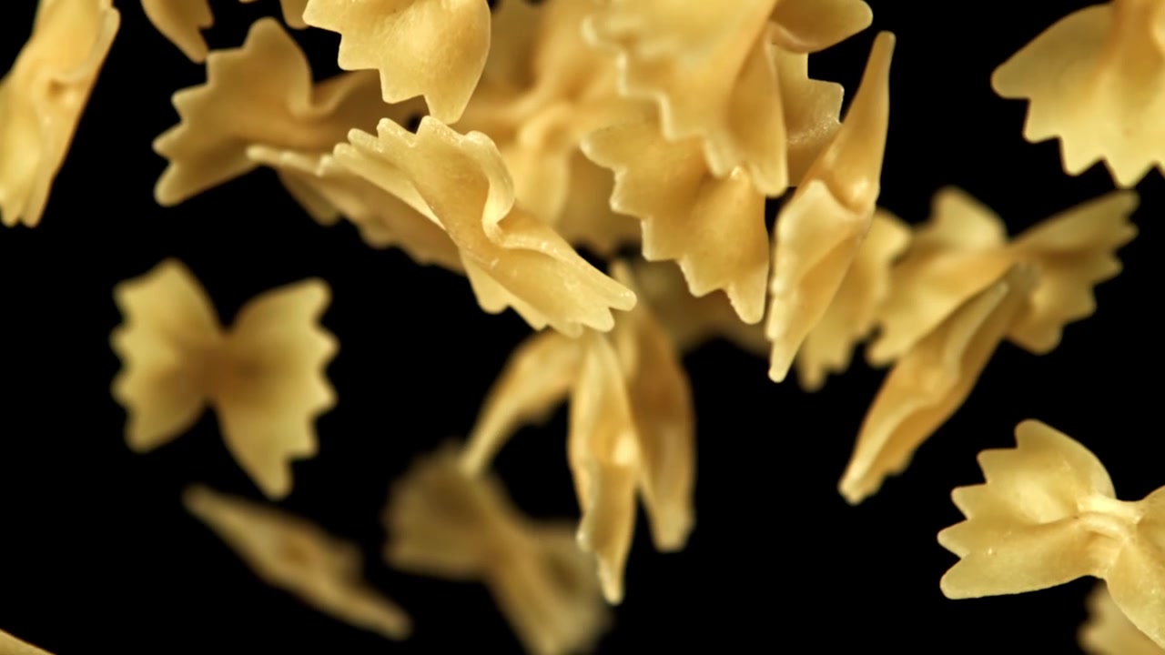 Pasta farfalle che cade al rallentatore su sfondo nero