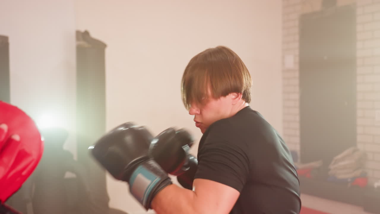 MMA fighter wearing black gloves throws powerful punch during intense sparring session, showcasing speed, focus, and determination while training with partner in gym environment filled with energy
