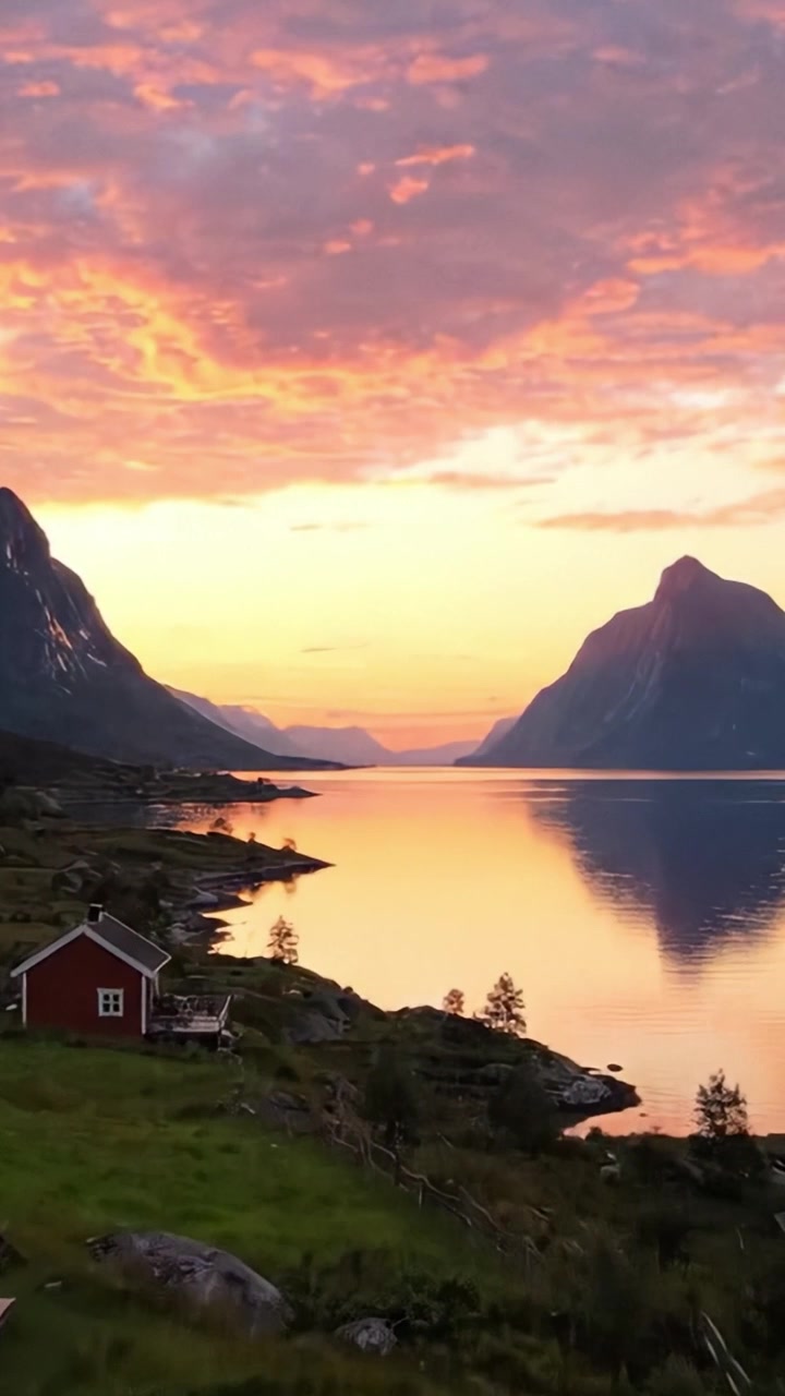 Betagende solnedgang over rolige vande: Et fredfyldt sceneri med majestætiske bjerge og charmerende huse, der reflekterer smukke farver i Norges betagende landskab.