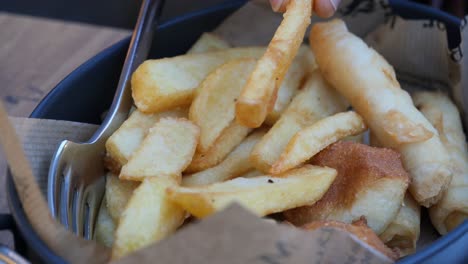 recogiendo a mano patatas fritas y pasteles fritos de un cuenco