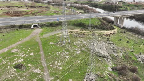 Aerial-perspective-of-two-transmission-towers,-overhead-power-lines