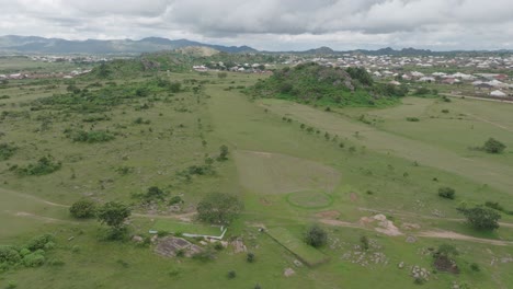 aerial - golf course surrounded by rocks and a settlement, forward descending