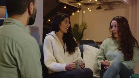 grupo relajado de amigos sentados en el sofá en casa o en un bar o cafetería hablando y bebiendo café juntos