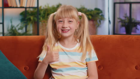 happy child kid girl looking approvingly at camera showing thumbs up like positive sign good news