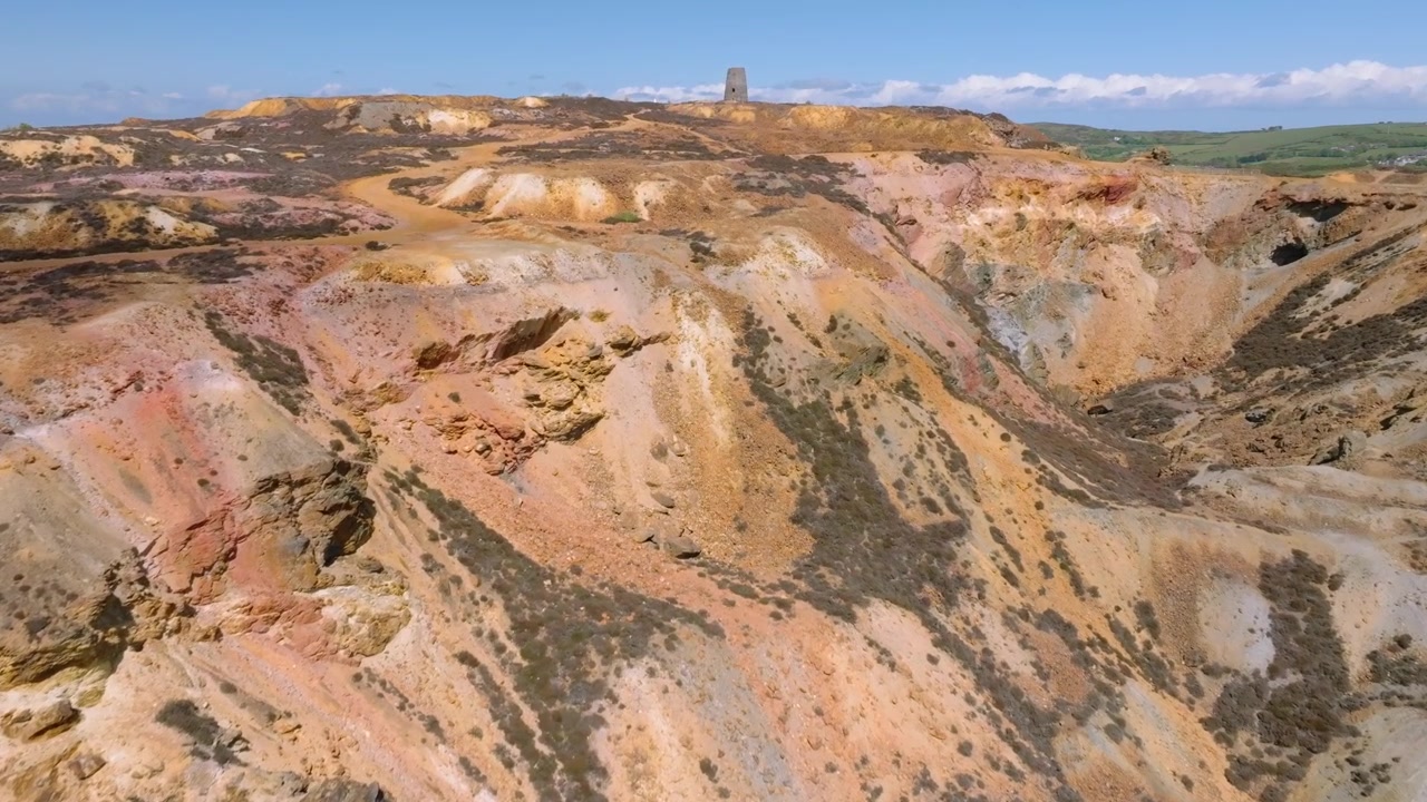 Miniera di rame di Parys Mountain, Amlwych, Anglesey, Galles, Regno Unito. Volo sopra il cratere principale verso un mulino a vento abbandonato sulla cima della collina.