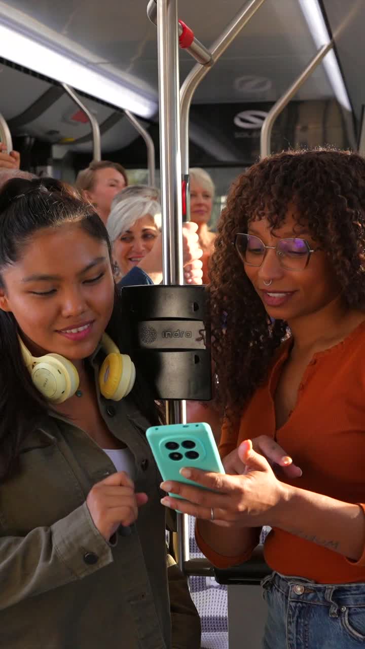 Two women using a smartphone on a bus