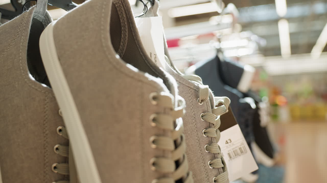 쇼핑몰의 랙에 매달린 신발의 클로즈업 뷰: 이 비디오는 현대적인 신발과 쇼핑 분위기를 보여주는 소매 환경에서 표시되는 다양한 스타일의 신발을 강조합니다.