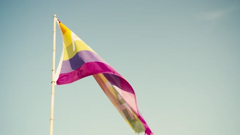 colorful peace flag fluttering in the breeze against a clear blue sky, vibrant symbol of harmony