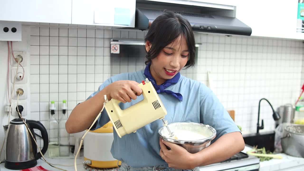mujer asiática haciendo pastel de tiramisu, agitando la masa en un cuenco usando una mezcladora en la cocina