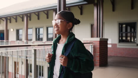school girl with backpack outside school building