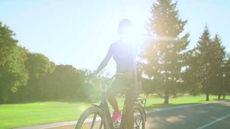 Tired-woman-bicyclist-wiping-sweat-from-face-while-cycling-in-summer-park