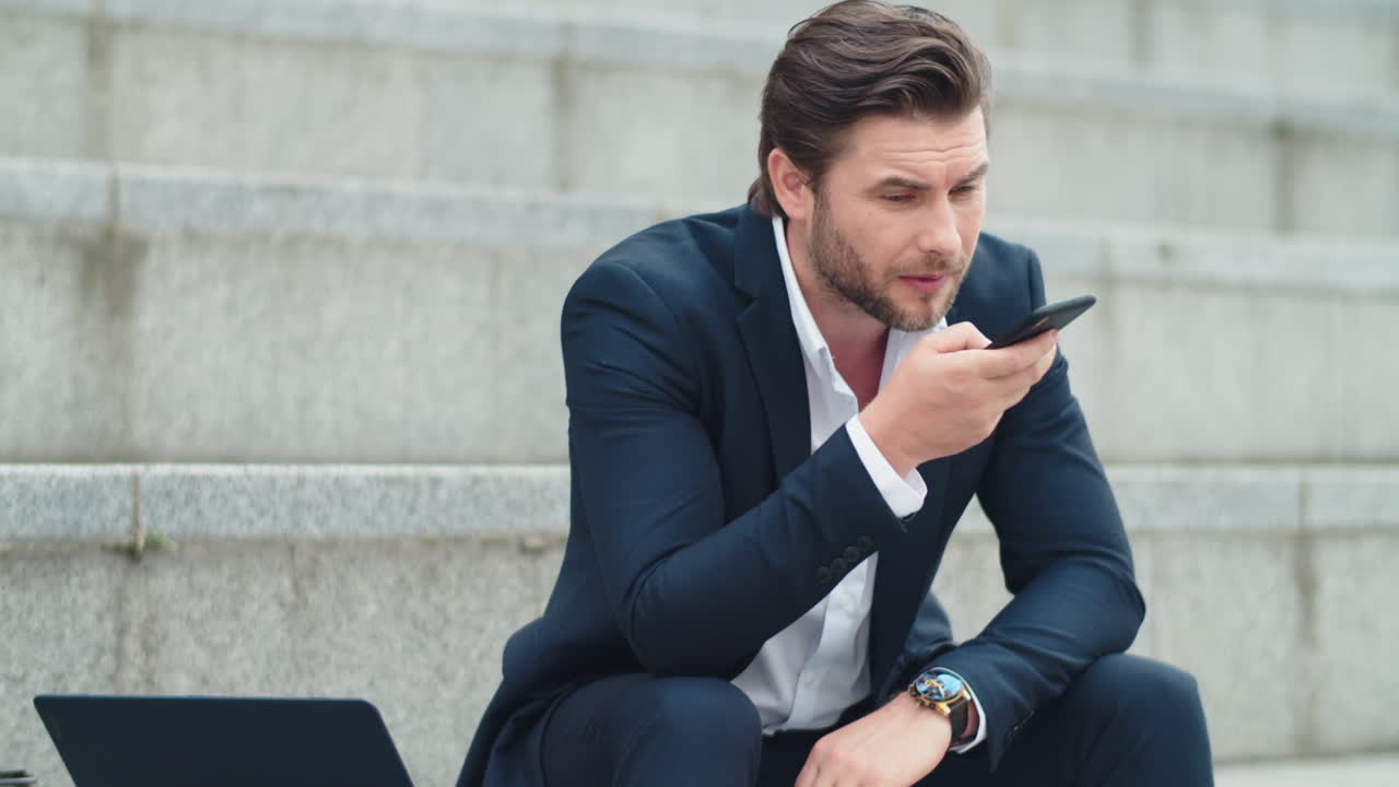 hombre de negocios hablando por teléfono altavoz en la calle. hombre sentado en las escaleras