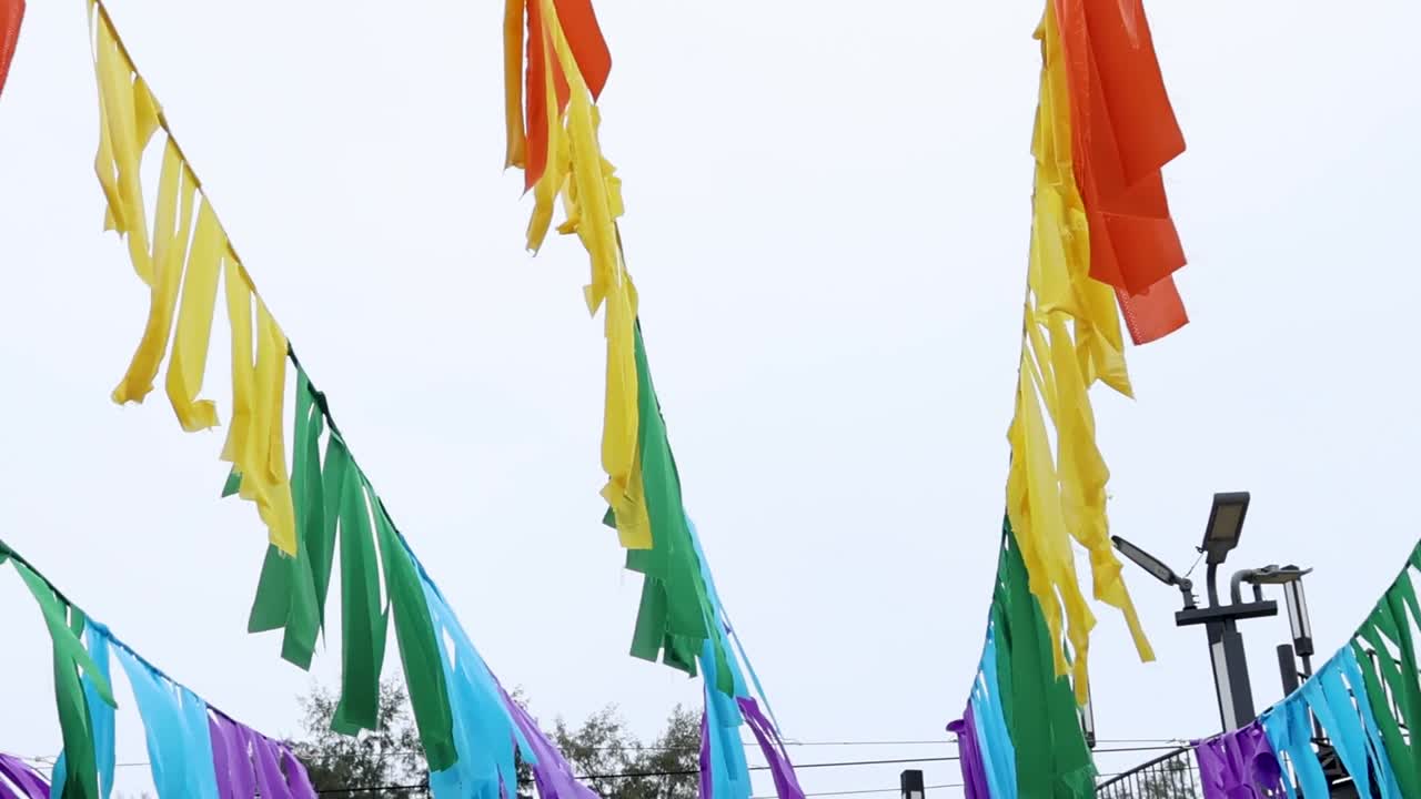 Brightly colored streamers in red, yellow, and green sway gently in the breeze against a clear sky.