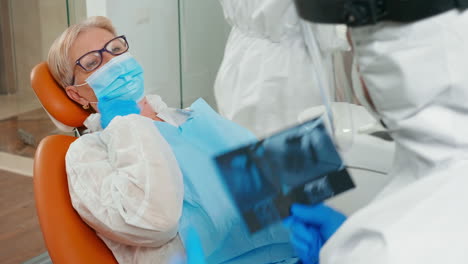 doctor with face shield reviewing panoramic dental x-ray image