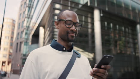 African-American-businessman-walking-through-city-using-smart-phone