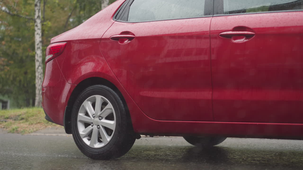 elegante coche rojo conduce por la carretera de asfalto en la ciudad en un día lluvioso