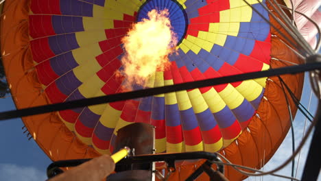 coloridos globos aerostáticos, quemador con llamas calentando aire en paracaídas, ángulo bajo