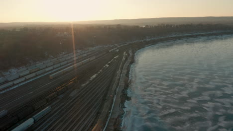 Aerial-shot-of-frozen-lake-near-industrial-lands-at-sun-set