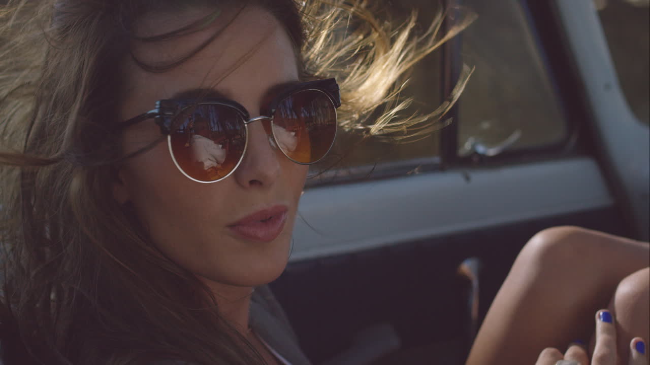 beautiful girl on adventure road trip in vintage convertible enjoying the wind in her hair