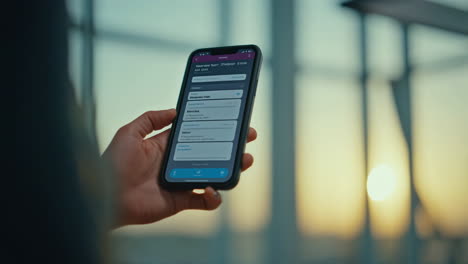 person holding a smartphone against a blurred sunset or sunrise background