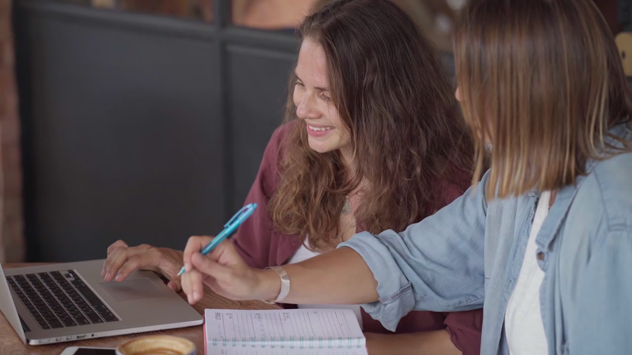 Due giovani donne che collaborano a un progetto in un caffè