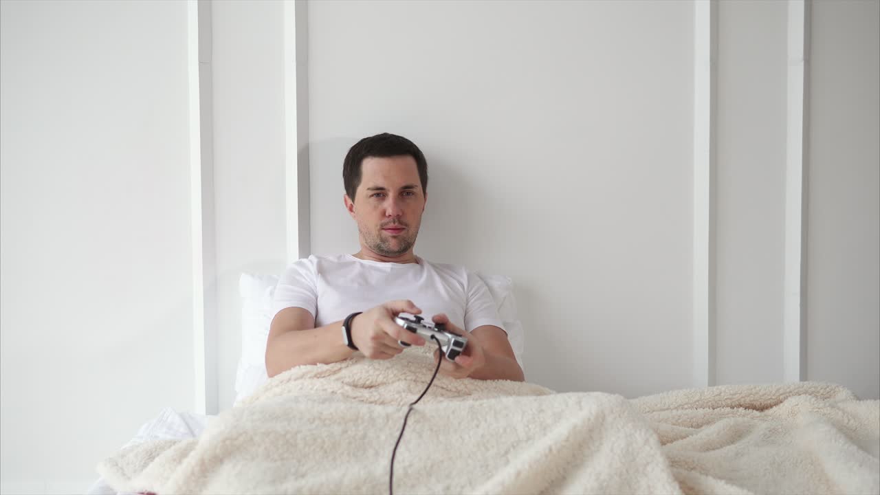 Uomo che gioca ai videogiochi a letto