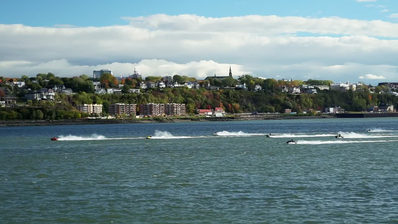 Jet skis racing across blue waters with a beautiful skyline over a hilltop
