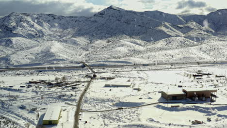 aerial view of snow flakes falling down over open farmland of northern california with mountains in distance